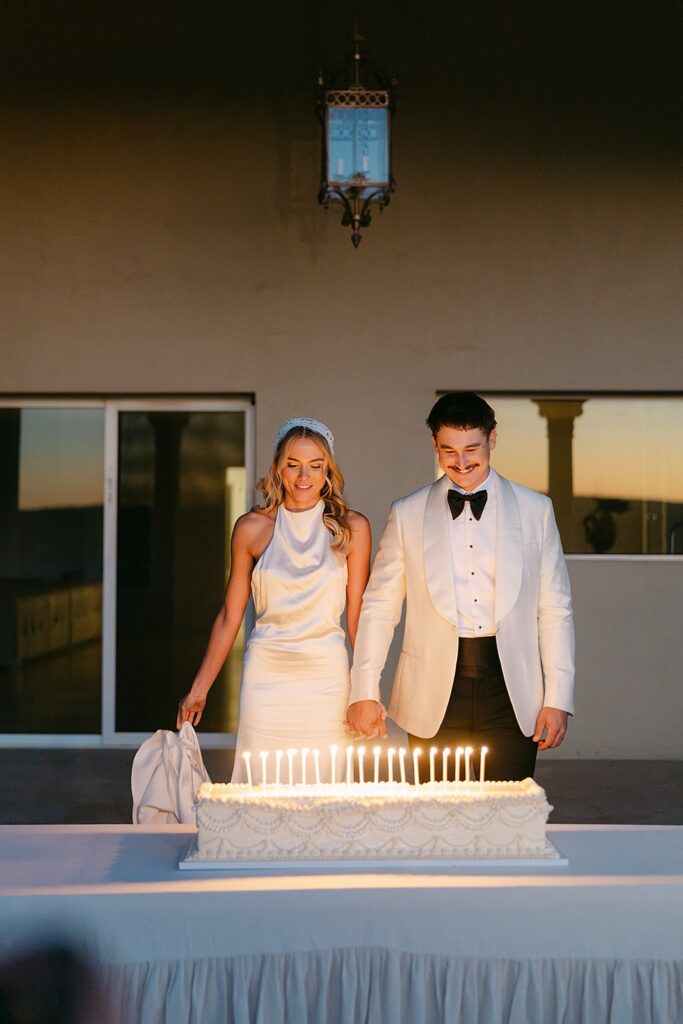 couple blowing out candles on wedding cake at alora macedon