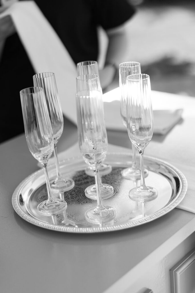 black and white portrait of champagne flute glasses on silver tray