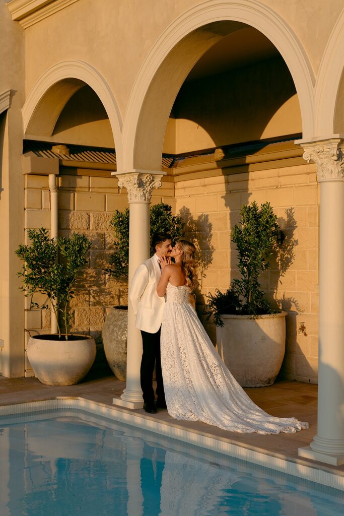 editorial portrait of couple kissing next to pool at golden hour