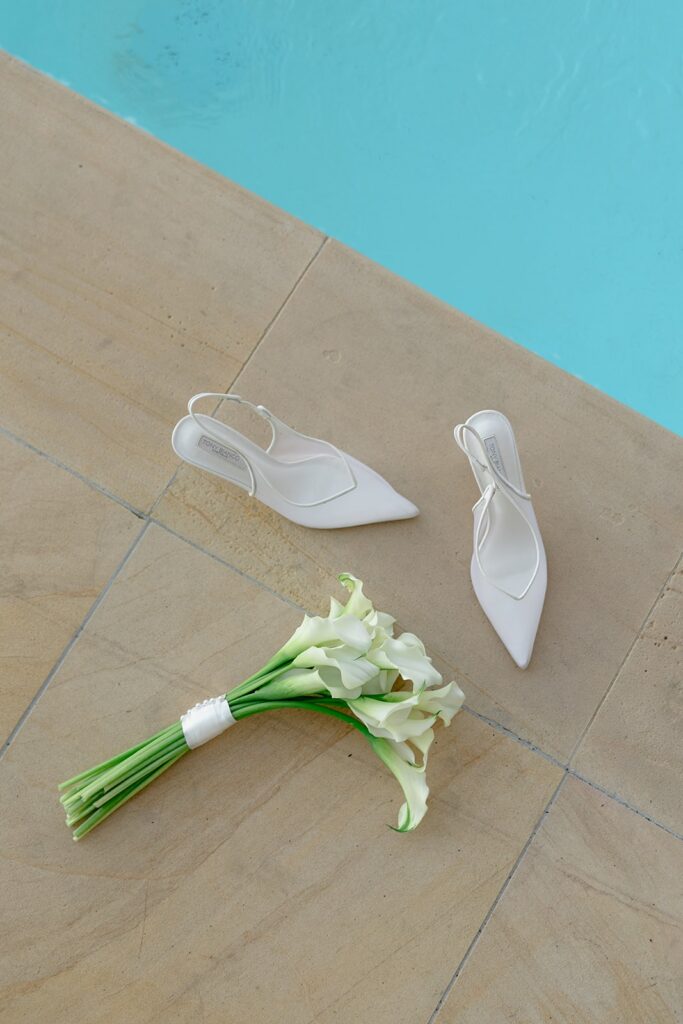 high fashion editorial portrait of bridal shoes and bouquet next to pool