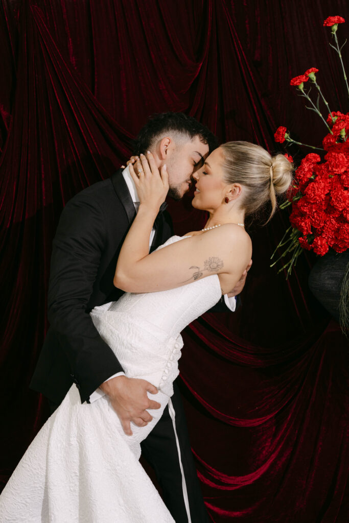 couple embracing with colour drenched draped backdrop during ceremony at the trust wedding venue