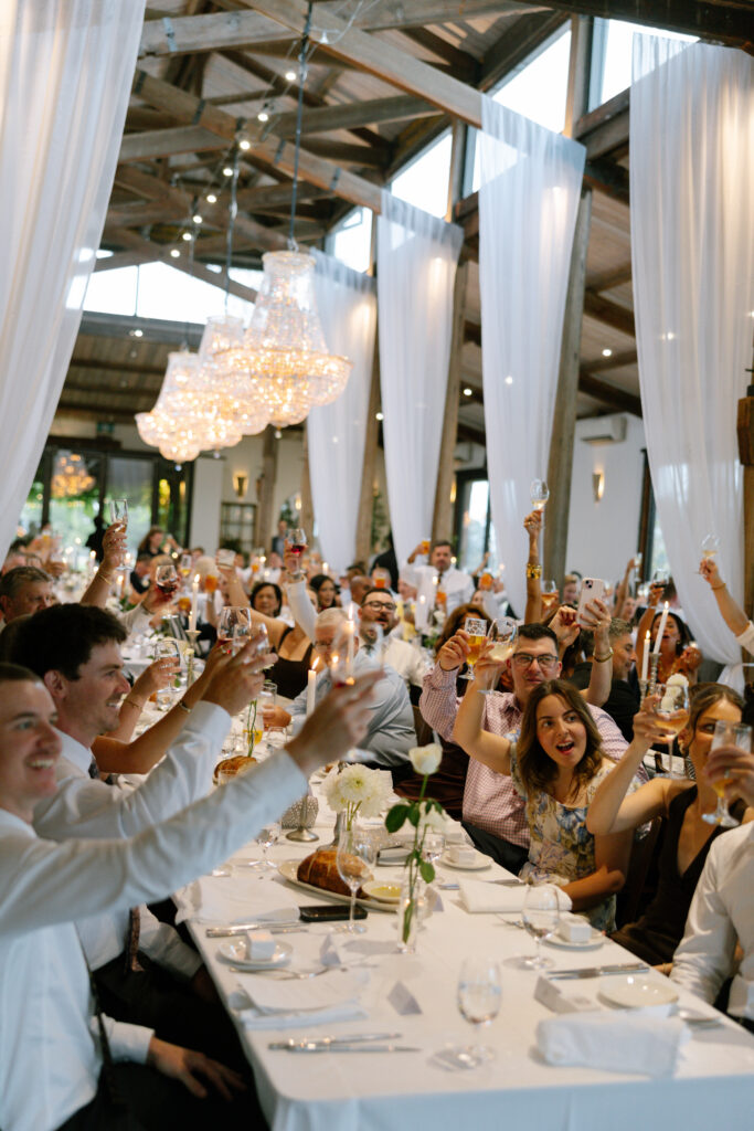 candid shot of guests toasting glasses during wedding reception at stones of the yarra valley 