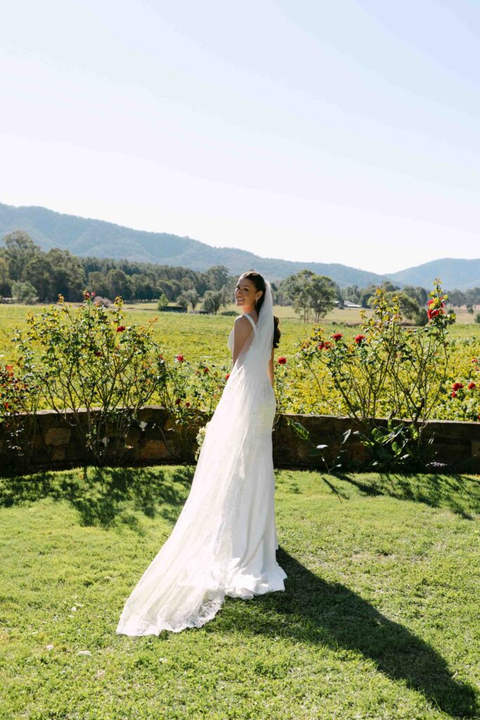 portrait of happy bride looking over her shoulder at the camera while standing in the garden at Feathertop Winery