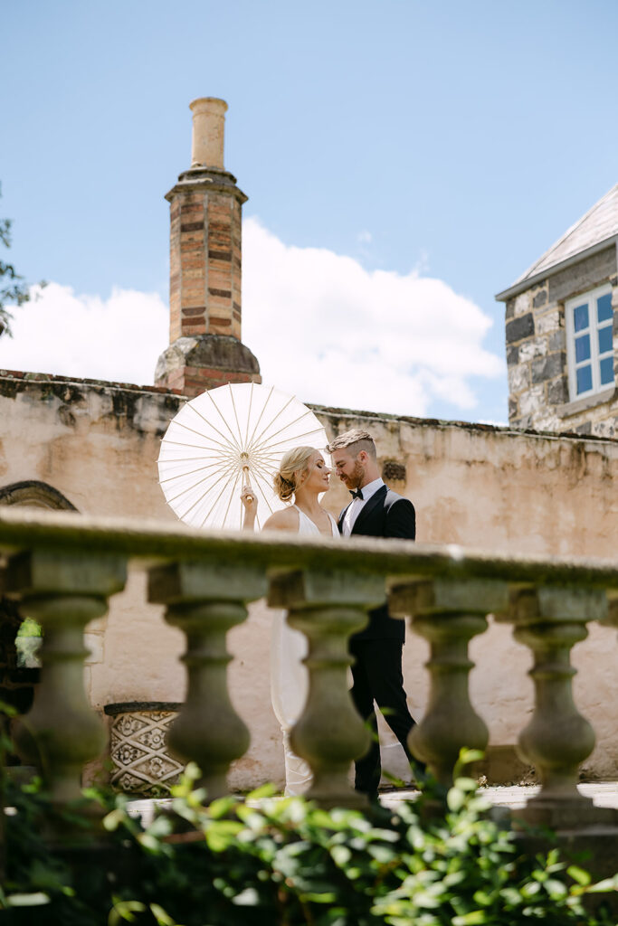 bride holding white parasol with husband at Montsalvat