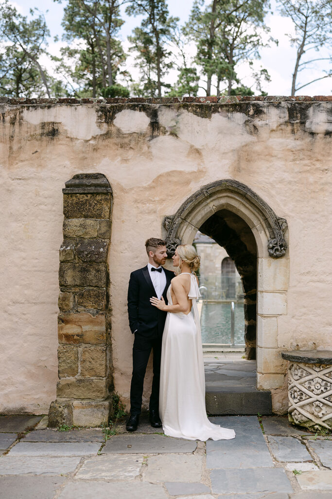 couple embracing next to wall at Montsalvat