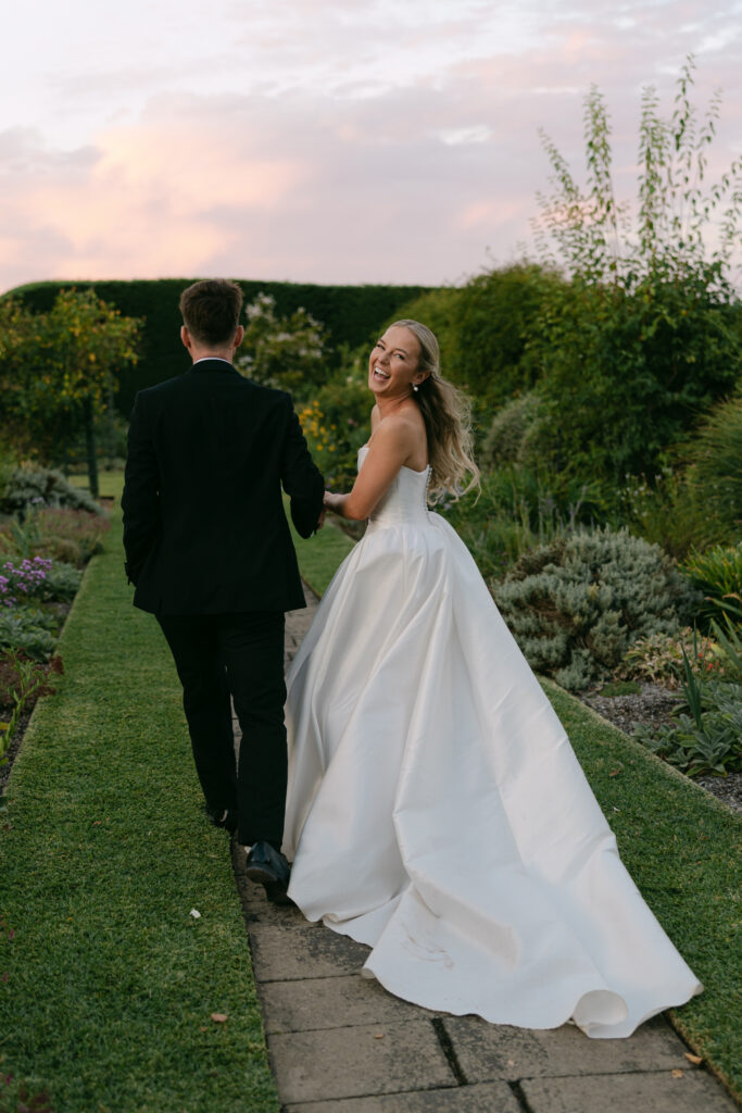 couple walking with bride turning back to face camera at Coombe Yarra Valley